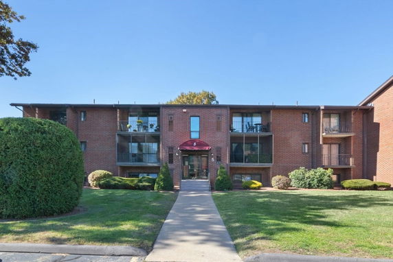 Front view of a three-story brick apartment building with balconies.