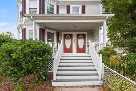Front view of a house with dual red doors and steps leading to the entrance.