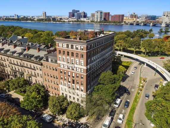 Front view of a multi-story brick apartment building near a river.