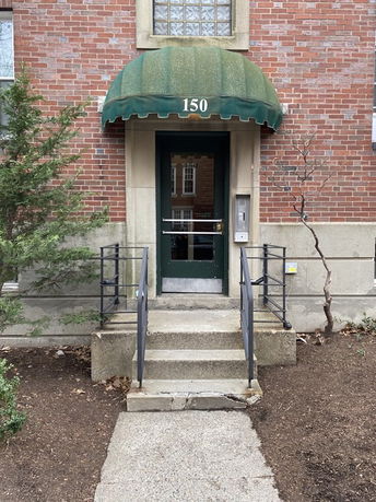 Front view of a building entrance with a green awning over the door.