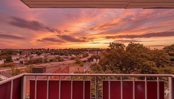 Panoramic view from a balcony overlooking a town with a sunset sky.