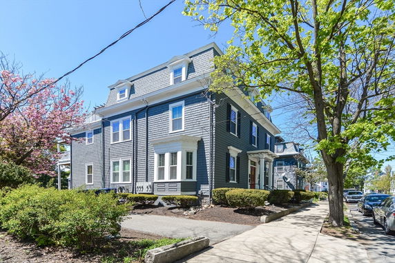 Front view of a large, two-story house with a gabled roof and dormer windows.