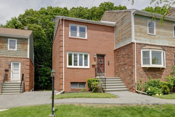 Front view of a two-story brick house with stairs leading to the entrance.