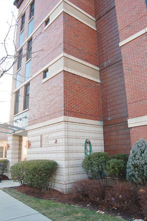 Front view of a multi-story brick building with small windows.