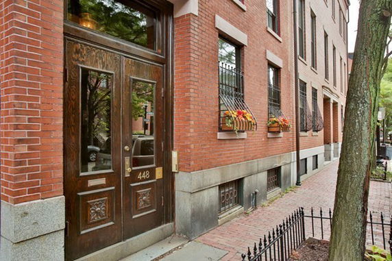 Front view of a brick building with decorative windows and a wooden door.