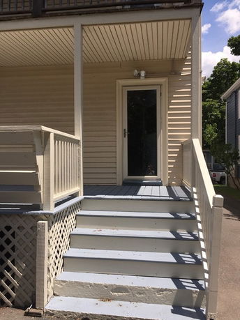 Front view of a house with a small porch and stairs leading up.