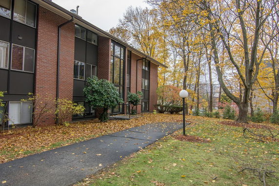 Front view of a multi-story brick building with large windows and a pathway leading to the entrance.