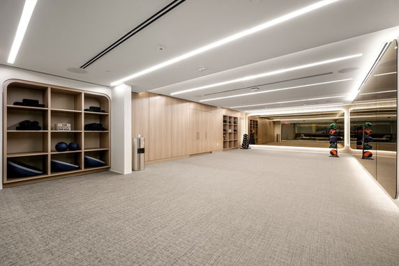 Interior view of a spacious club house with exercise equipment and large mirrors.