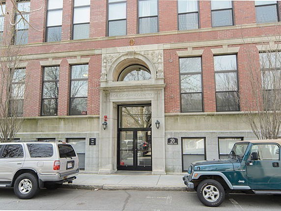 Front view of a multi-story brick building with an arched entrance.