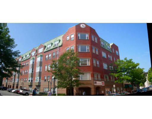 Front view of a multi-story brick building with gabled roof and large windows.