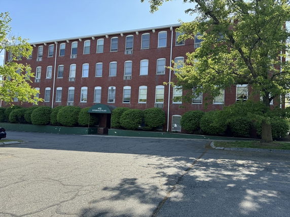Front view of a three-story brick building with multiple windows.