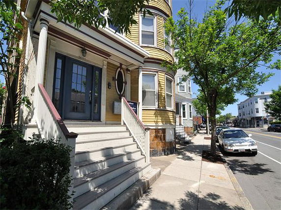 Front view of a three-story house with a stairway leading to the entrance.
