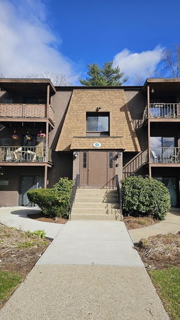 Front view of a multi-story apartment building with a central entrance and balconies.