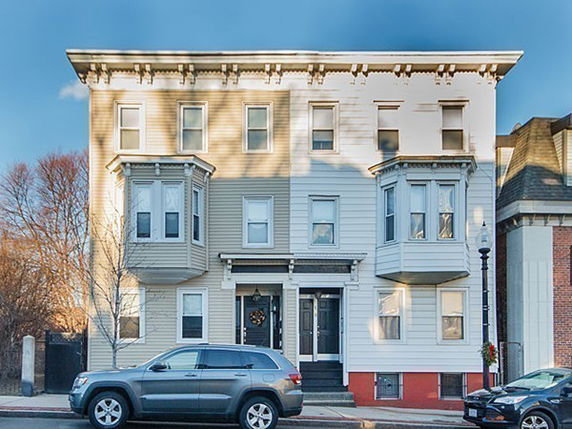 Front view of a three-story residential building with bay windows and a symmetrical facade.