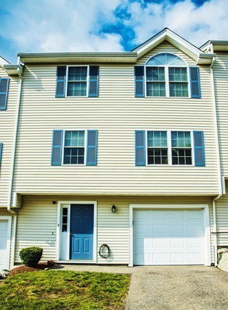 Front view of a multi-story house with a garage and blue shutters.