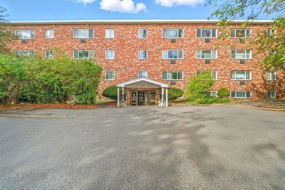 Front view of a four-story brick building with multiple windows and a covered entrance.