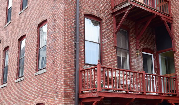 View of a brick building with multiple windows and a small balcony.