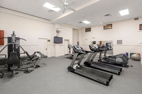 Indoor gym area with exercise equipment including treadmills and workout machines.