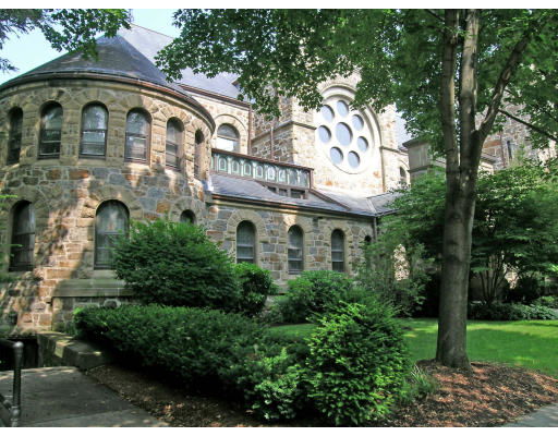 Front view of a stone building with arched windows and circular feature.