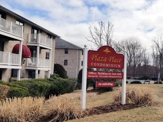 Front view of a condominium building with balconies and a signboard for Plaza Place Condominium.