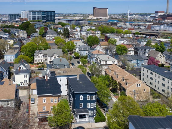 Aerial view of a suburban neighborhood with multiple houses and buildings surrounded by trees.