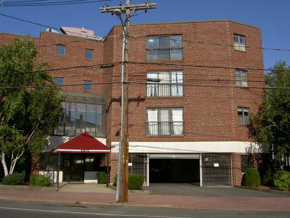 Front view of a multi-story brick building with large windows and a glass entrance.