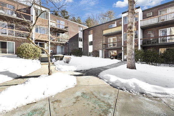Front view of a multi-story apartment building with balconies in a snowy landscape.