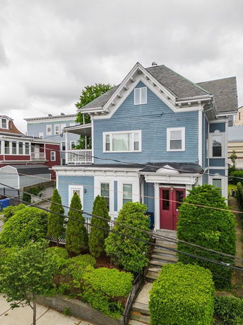 Front view of a two-story house with a blue facade and a red door.