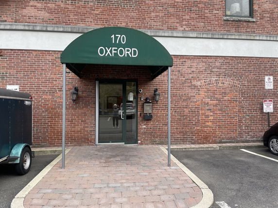 Front entrance of a brick building with a green awning labeled '170 Oxford'.