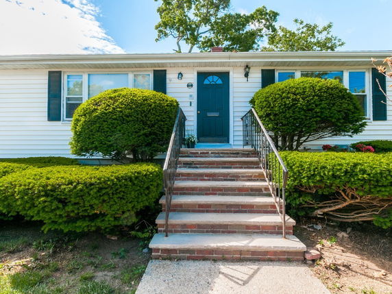Front view of a single-story house with stairs leading to a blue door.