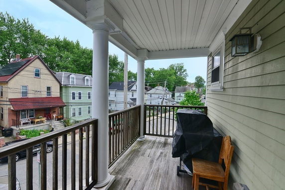 View from a covered balcony overlooking a residential street with multiple houses.