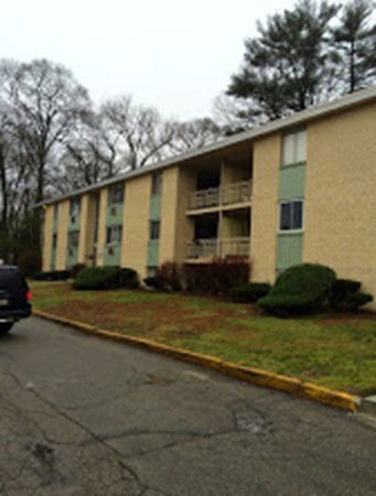 Front view of a low-rise apartment building with balconies and a driveway.