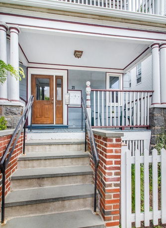 Front view of a house with a porch and brick steps leading up to a wooden door.