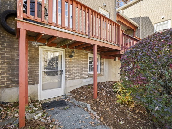 Exterior view of a house with a red wooden deck and a glass door entry.