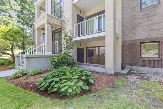 Front view of a multi-story building with balconies and a small garden.