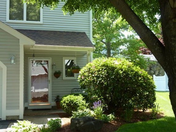 Front view of a house with a small porch and overhanging roof.