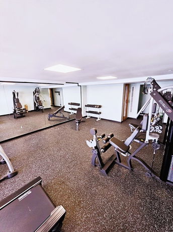 Indoor gym area with exercise equipment and mirrored wall.