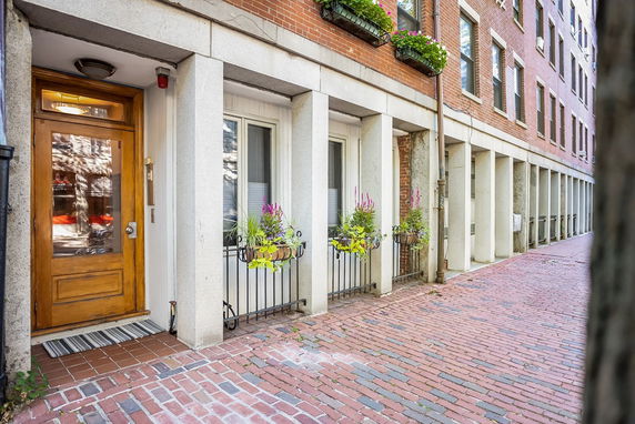 Front view of a brick residential building with flower boxes on windows and wooden door.