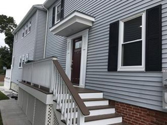 Front view of a two-story house with gray siding and steps leading to the entrance.