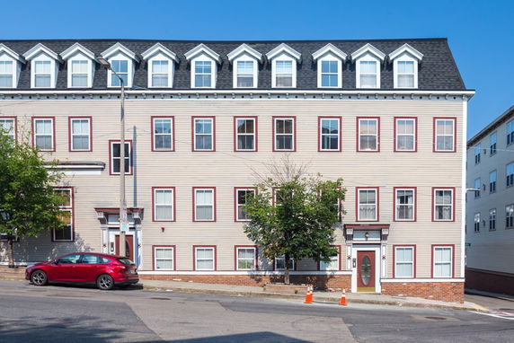 Front view of a large multi-story building with multiple windows and a gabled roof.