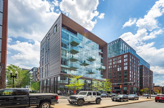 Front view of a modern multi-story building with glass facades and balconies.