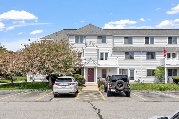 Front view of a three-story residential building with white siding and balconies.