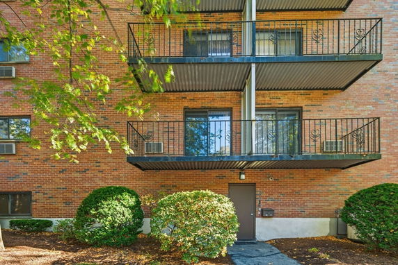 Front view of a multi-story building with brick facade and balconies.