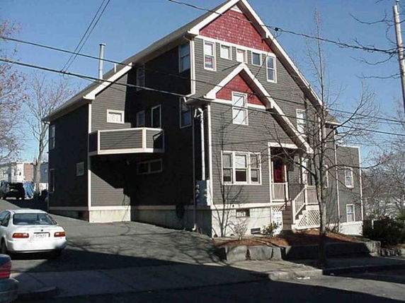 Front view of a multi-story house with a pointed roof and multiple windows.