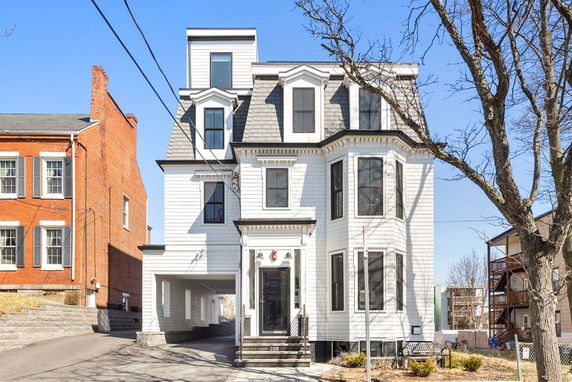 Front view of a multi-story house with a prominent bay window and dormer windows.