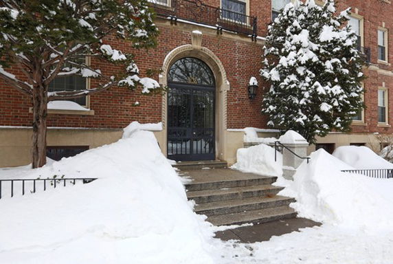 Entrance view of a brick building in winter with snow-covered steps.