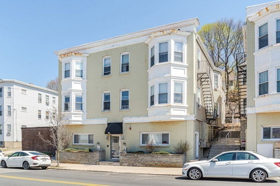 Front view of a three-story apartment building with a beige facade and white trim.