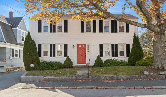 Front view of a two-story house with red door and black shutters.