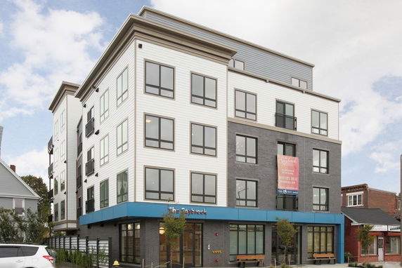 Front view of a modern multi-story apartment building with large windows.