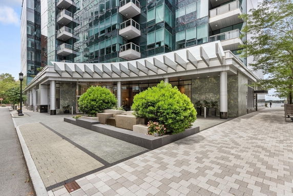 Front view of a modern multi-story building with glass exterior and balconies.
